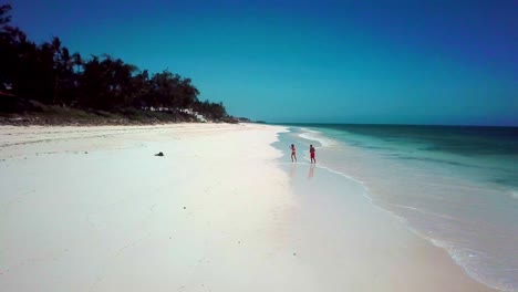 couple dancing at the white-sand beach of kenya in east africa. - aerial pullback