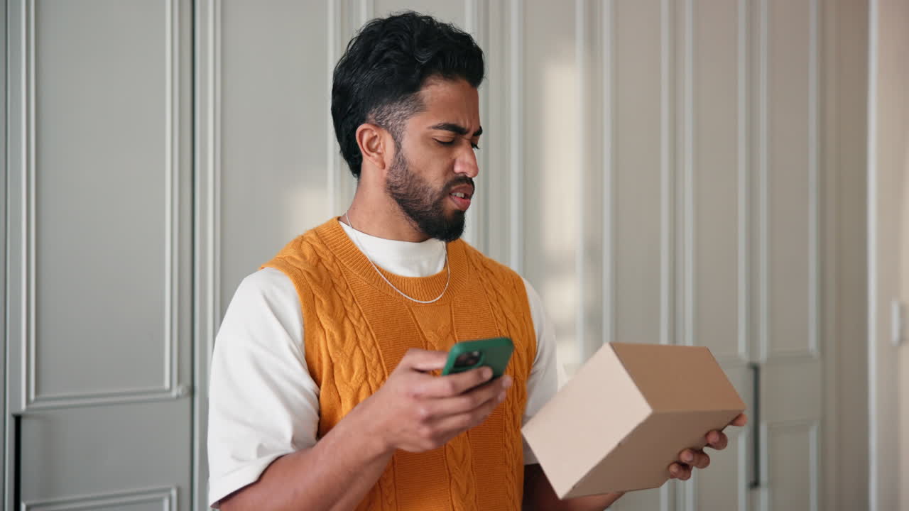 Worried man checking phone while holding a box