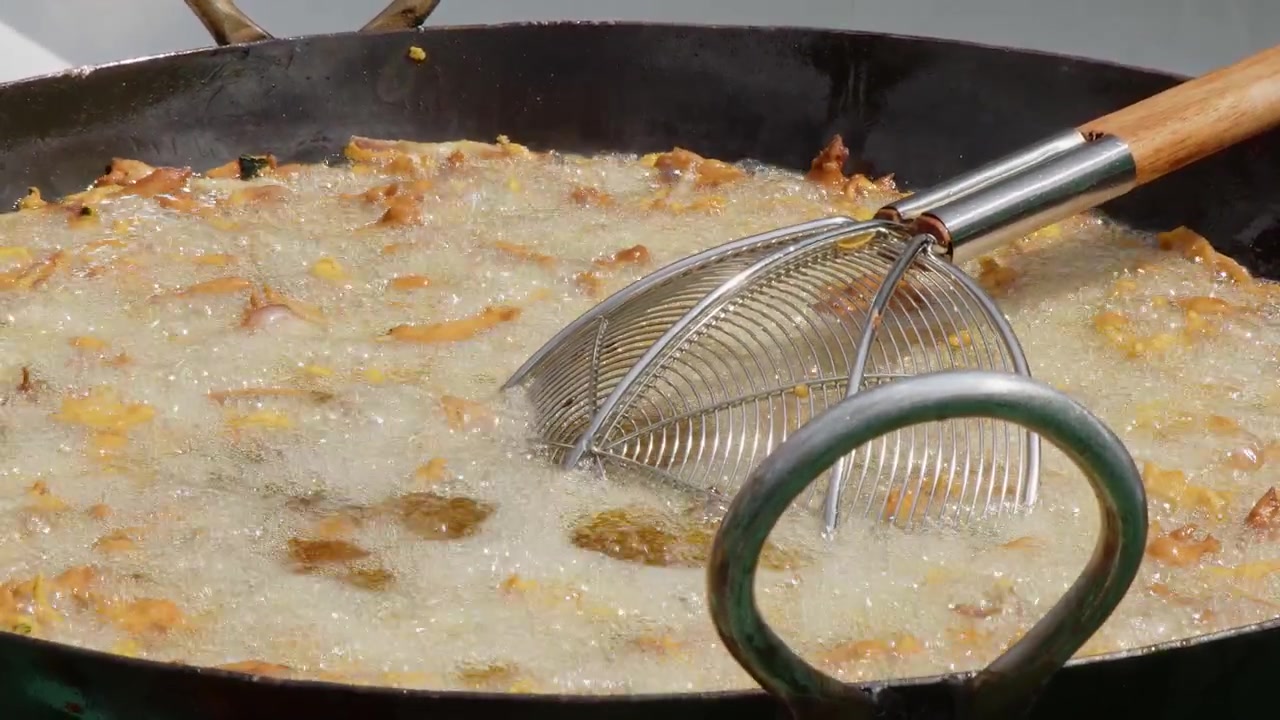 Primo piano di un calderone con olio bollente che frigge pakora, in un festival all'aperto.
