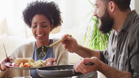 Video-De-Una-Feliz-Pareja-Diversa-Hablando-Y-Sirviendo-El-Desayuno-En-La-Mesa