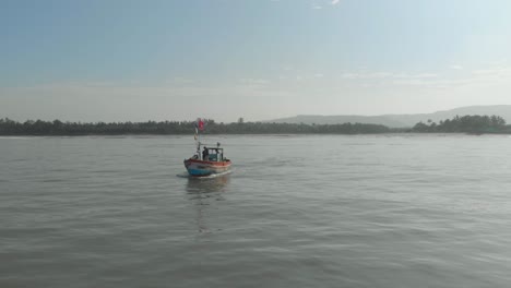 Drone-shot-of-small-colourful-Indian-fishing-boat-going-out-to-sea-looking-towards-shore