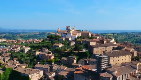 Village-on-top-of-a-hill-surrounded-by-cultivated-fields-and-woods,-drone-parallax