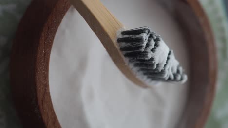 bamboo toothbrush with powder in wooden bowl
