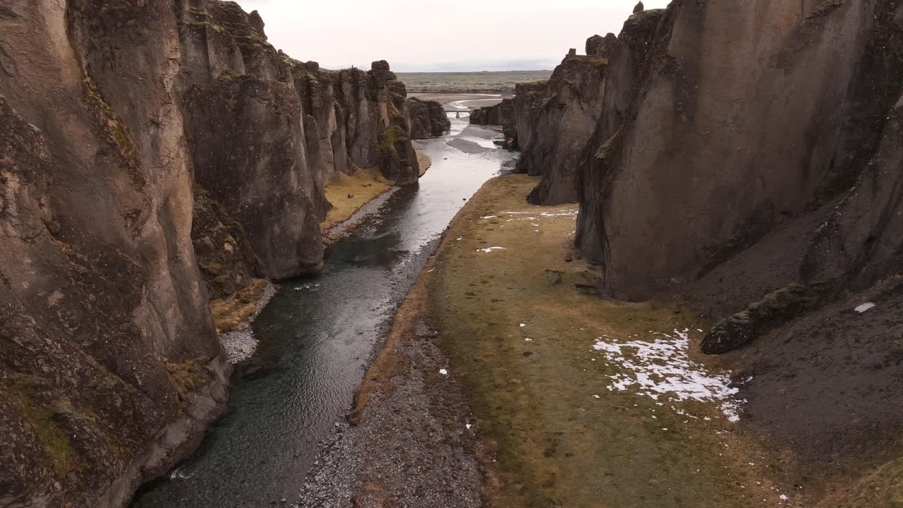 Aerial view of the dramatic Fjaðrárgljúfur Canyon in Kirkjubæjarklaustur, Iceland, showcasing the narrow river winding through steep rocky cliffs.
