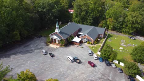 an orbiting drone shot with trees in the foreground of a church in rural south carolina