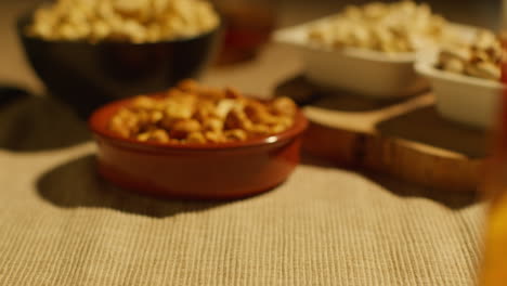 close up of hand choosing from bowls of cashews dry roasted peanuts and pistachio nuts in studio 2