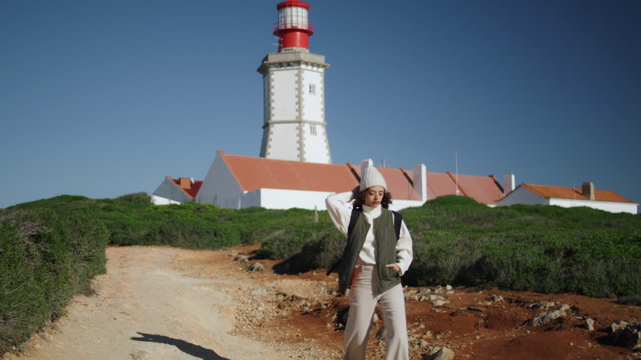 una chica turista caminando por el camino del faro en un día soleado. una mujer serena descansa en la primavera.