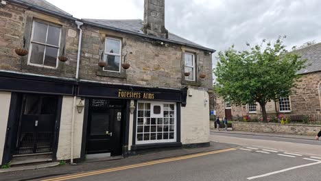 pedestrians stroll by a historic scottish pub