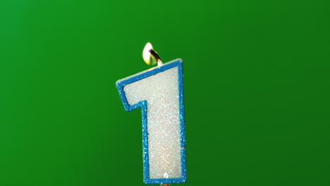 one birthday candle flickering and extinguishing on green background