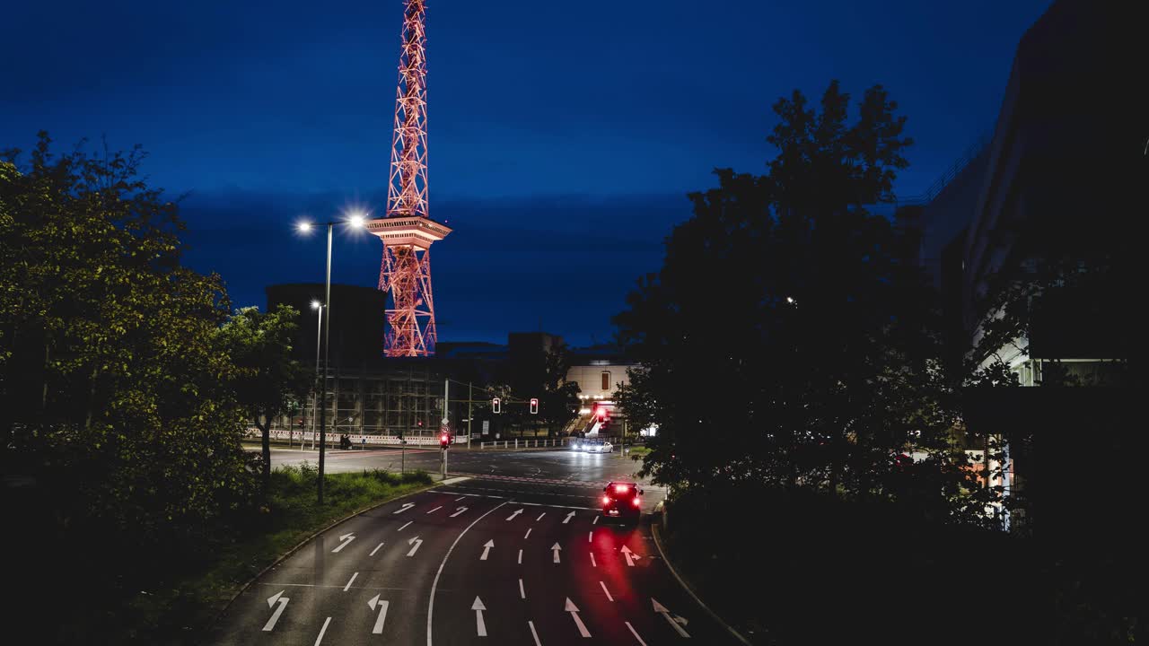 Timelapse of cars passing road crossing near Funkturm Berlin, Germany, sight illuminated in many colors during festival of lights