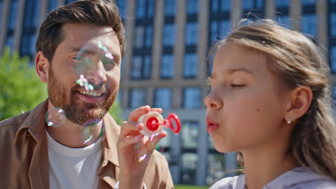 Small kid enjoy blowing soap bubbles outdoor closeup. Cheerful family playing