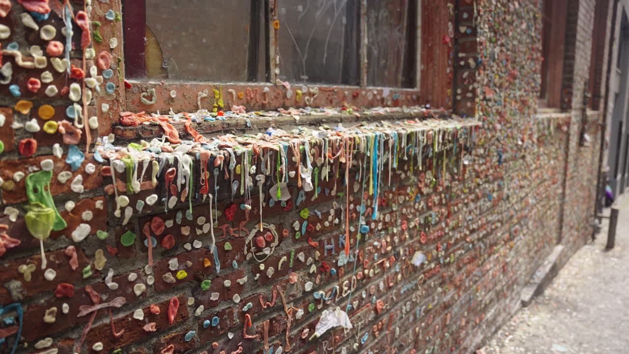 Fixed shot of brick wall and window fully covered with chewed gum in Seattle