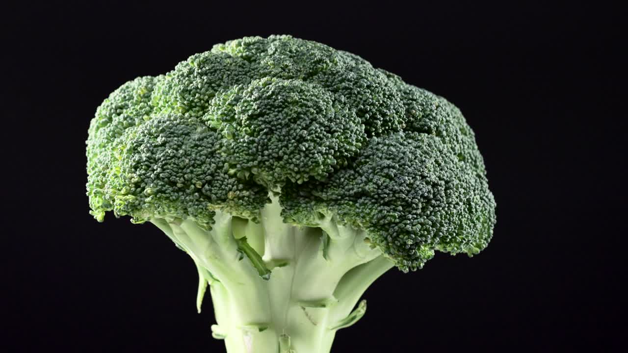 Close up of fresh raw broccoli rotating over black background