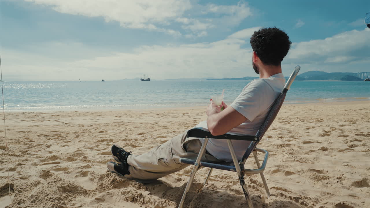 Tourist enjoying caipirinha cocktail sitting on sandy Brazilian beach, summer vacation vibe