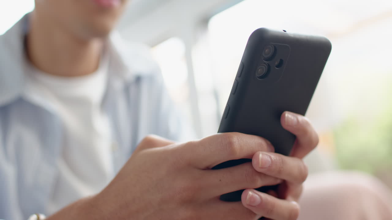 Texting and browsing internet, teenage boy holding smartphone at home