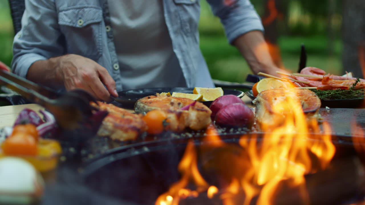Fuoco vivo in un barbecue in giardino. Donna che prepara cibo sulla griglia all'aperto