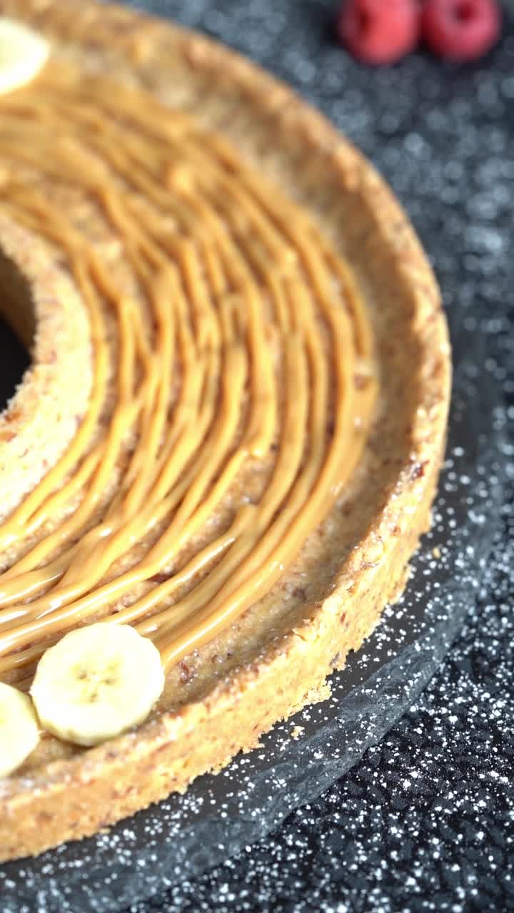 Um chef adiciona rodelas de banana a um bolo, close-up, insert