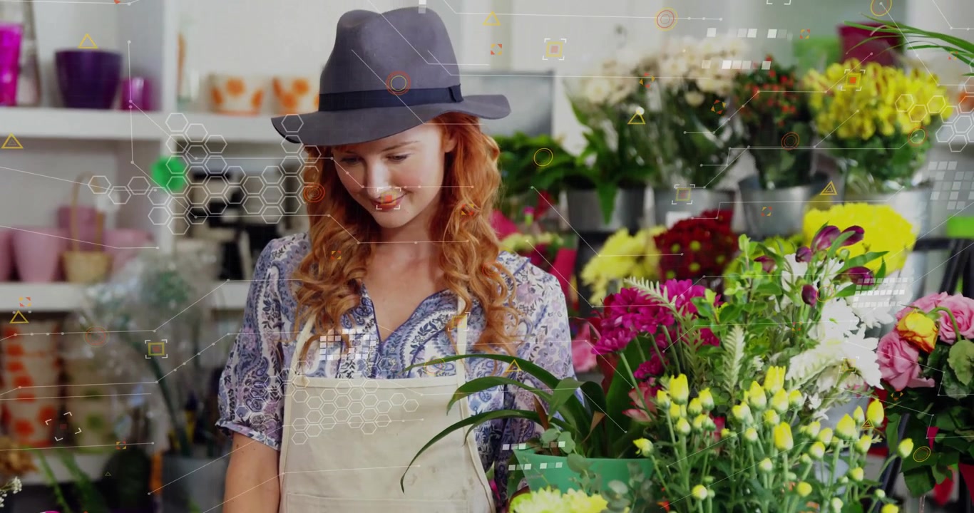 Fiorista che inserisce dati su un laptop in un negozio di fiori, generando una griglia esagonale sui fiori per l'inventario.