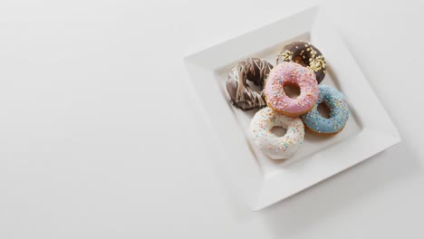 video of donuts with icing on white plate over white background