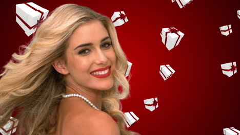 una rubia glamurosa lanzando el cabello contra los regalos de navidad que caen