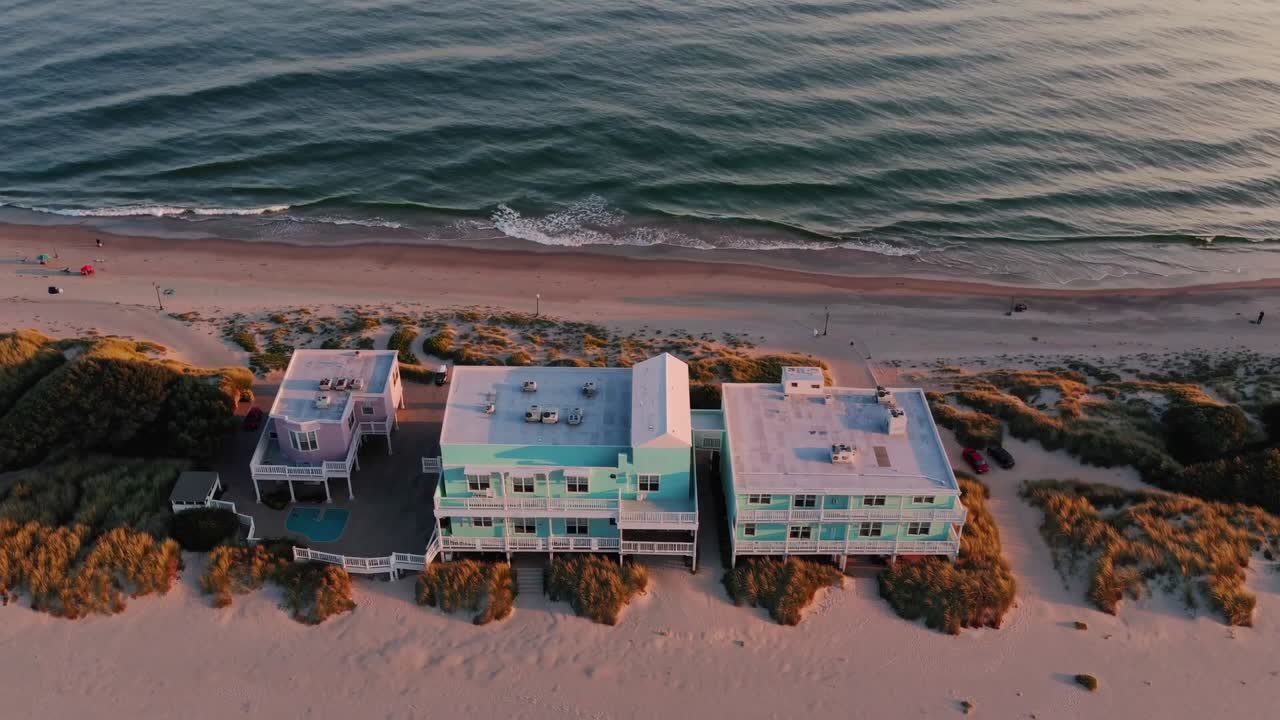 Aerial view of coastal beach houses at sunset, showcasing vibrant colors and serene waves, highlighting the tranquil atmosphere of seaside living and natural beauty