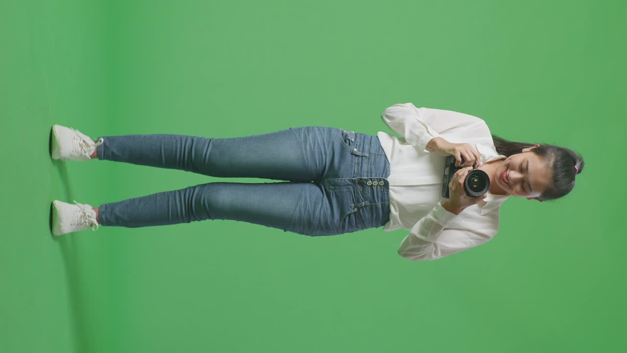 Full Body Of Asian Photographer Changing Lens Of Camera Before Using It Taking Pictures While Standing On Green Screen Background In The Studio
