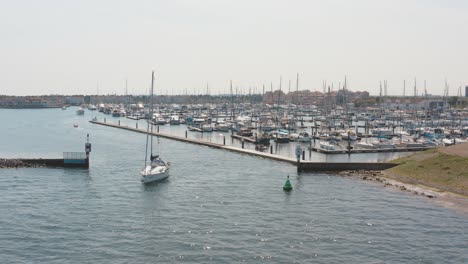 drone cinemático - toma aérea de un barco navegando en el océano con un puerto deportivo en el fondo con veleros en un día soleado en zelanda en el mar del norte, países bajos, 30p
