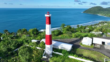 the red and white lighthouse faces directly into the ocean on the border of indonesia and papua new guinea