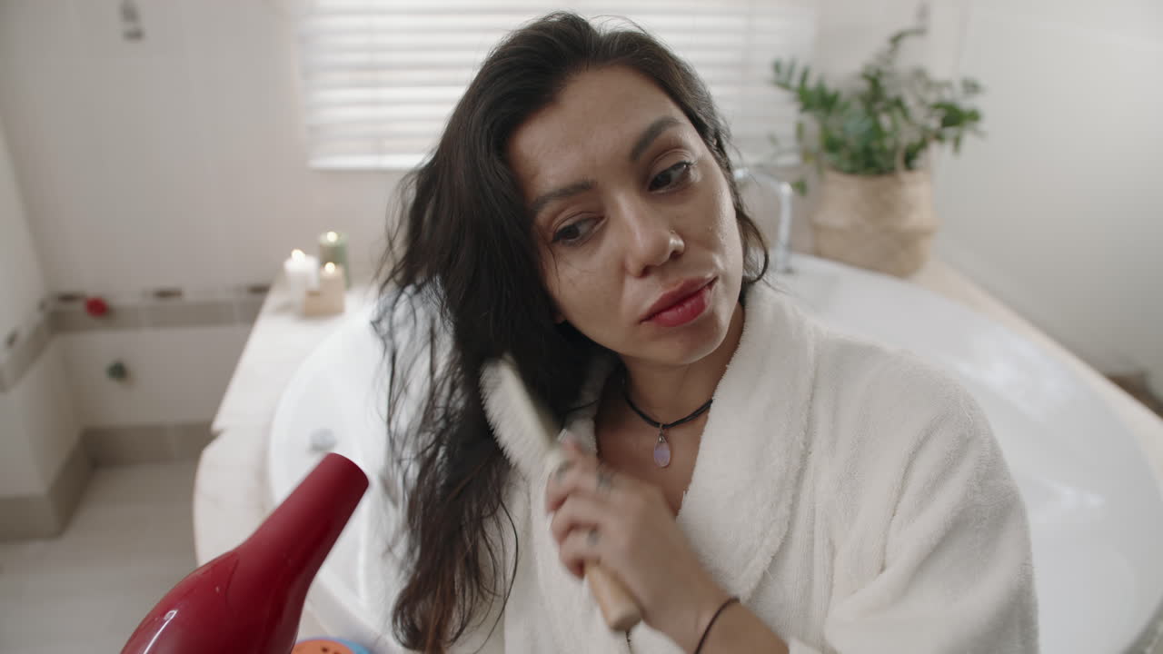 Young Woman Blow-Drying Hair in Bathroom