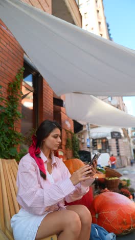 woman taking a photo at an outdoor cafe