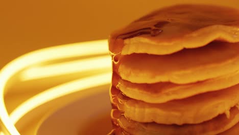 video of maple syrup pouring into pancakes on orange background