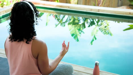 by pool, woman meditating with headphones, finding peaceful moment, copy space