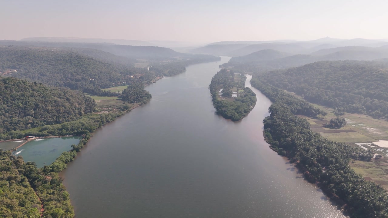Expansive aerial view of the wide Karli River flowing through a lush green valley with a large island in Maharashtra, India.