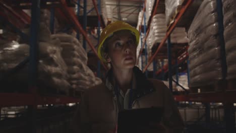 Female-warehouse-worker-patrolling-warehouse-corridor-at-night-4k