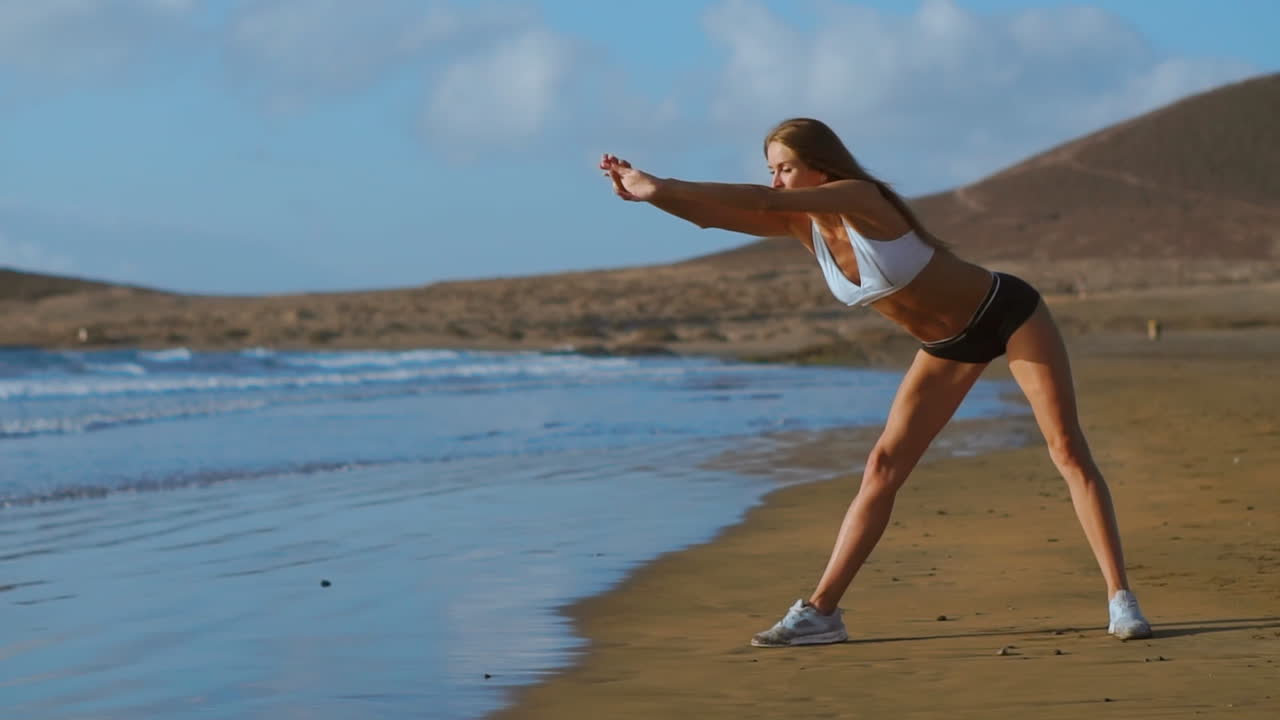 mujer estirando las piernas y los isquiotibiales haciendo postura de yoga de estiramiento en la playa. mujer de fitness relajándose y practicando deporte y yoga.