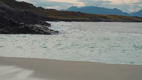 Gentle-waves-are-crashing-on-the-rocks-and-spilling-on-the-sandy-beach