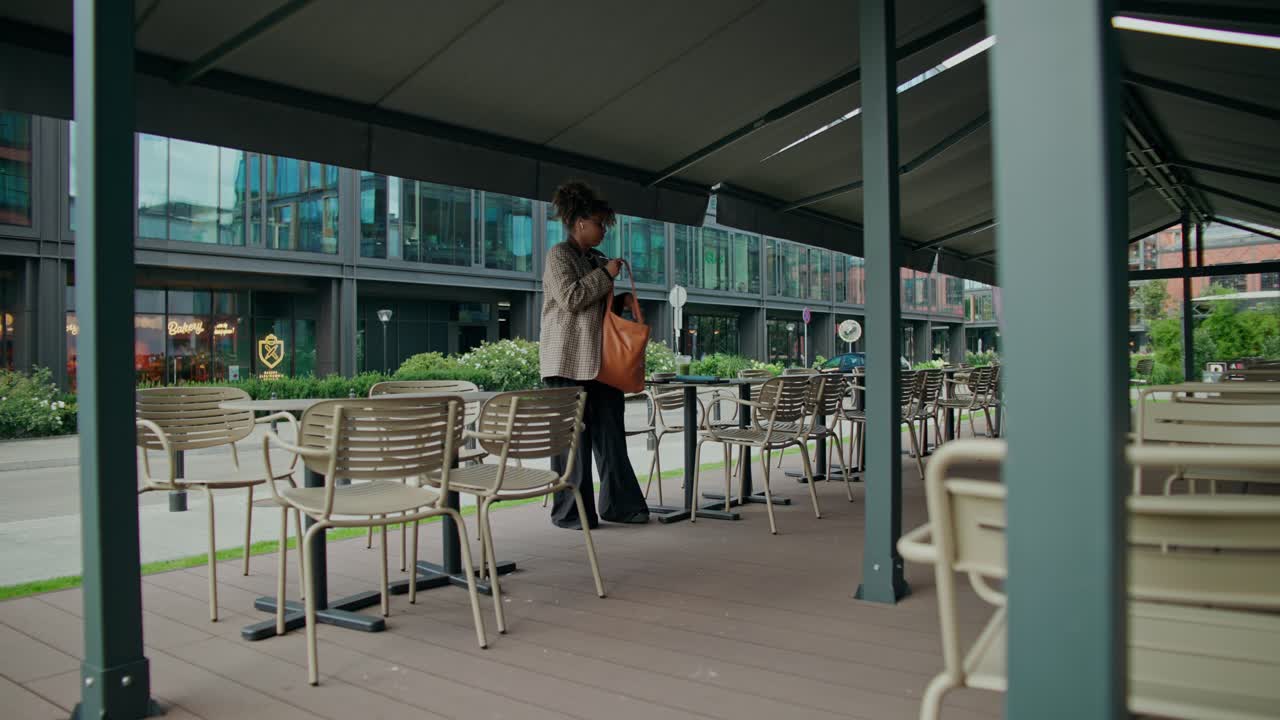 Mujer colocando mesas en una cafetería al aire libre