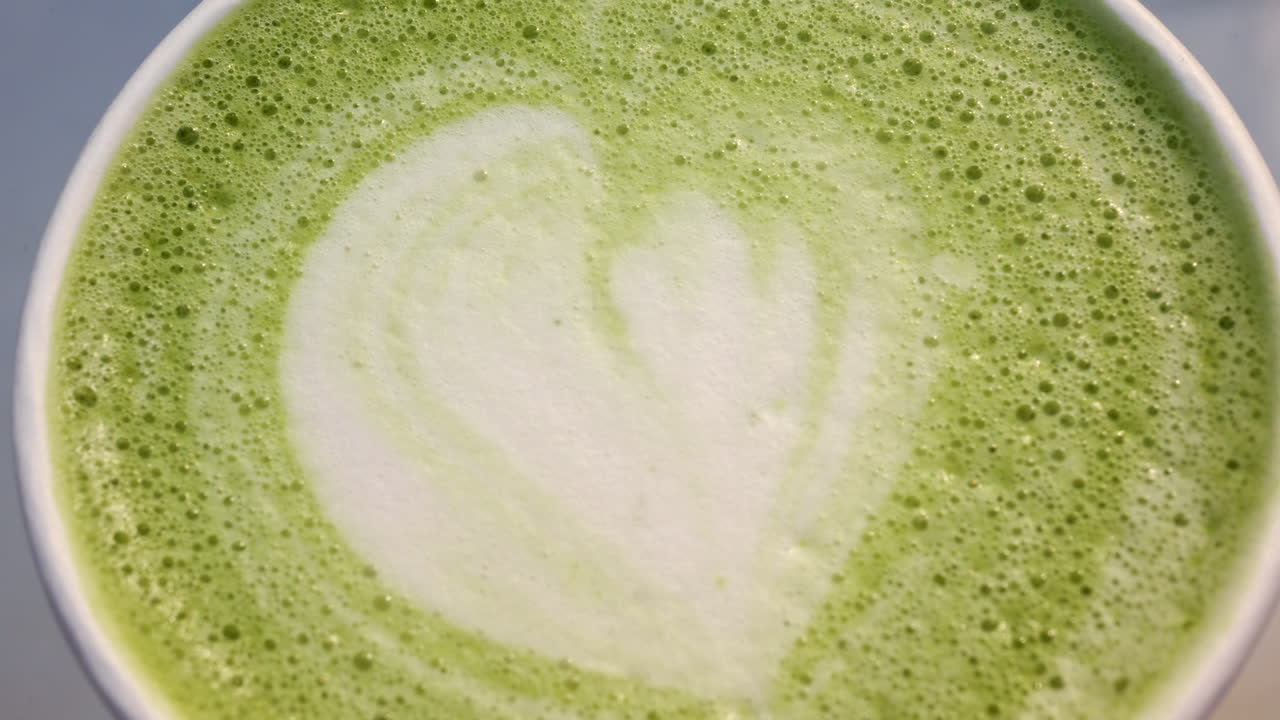 Foto macro da espuma de matcha latte com textura suave e cremosa e detalhes delicados de latte art.