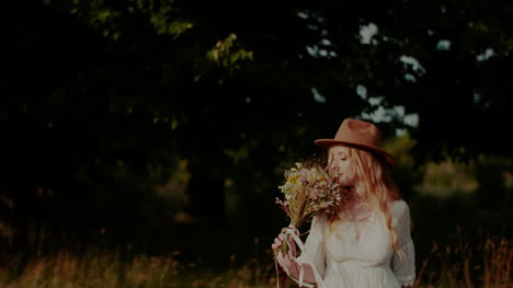 atractiva mujer boho caminando en un prado en verano sosteniendo flores en la mano 3