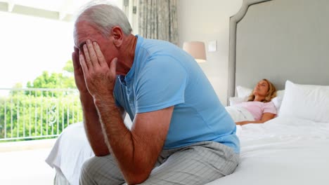 Worried-senior-man-sitting-in-bedroom