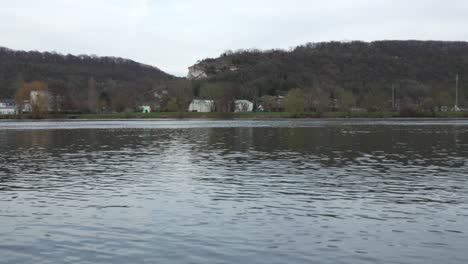 static serene view of flowing river glistening and reflecting overcast sky above