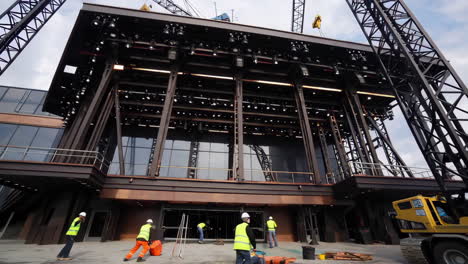 construction of a modern building with cranes and workers