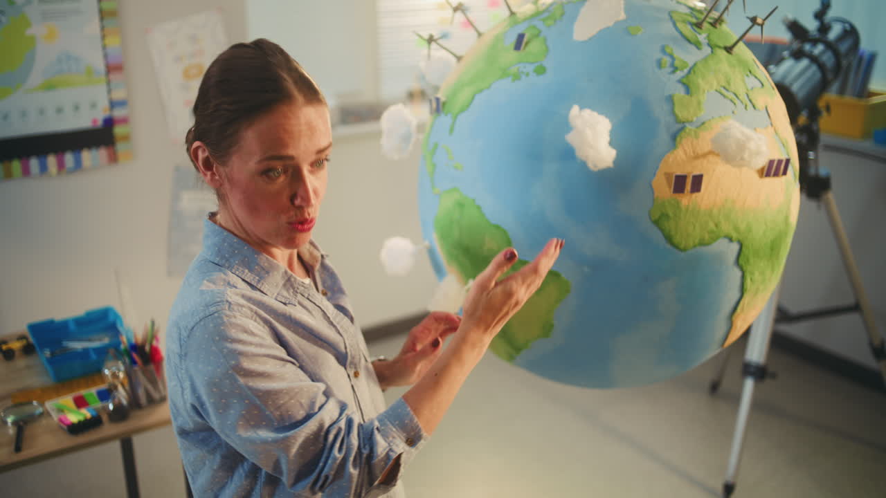 Female School Teacher Educating Science and Renewable Energy Sources Using Model of Planet Earth