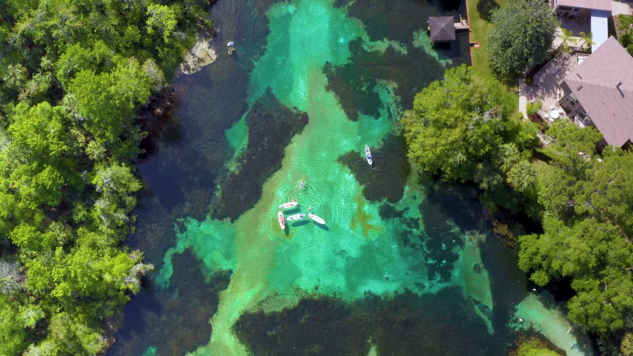 drone disparado mirando hacia abajo en el río arco iris como kayaks y barcos flotan a lo largo