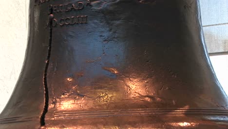 the camera pans from the bottom to the top of the liberty bell where we see part of the inscription