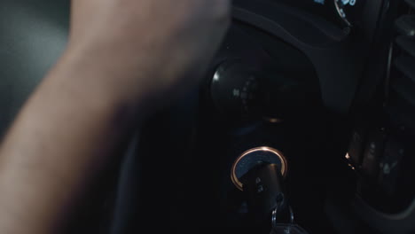 una mano que se agacha detrás del volante y gira la llave de un auto para arrancar un automóvil