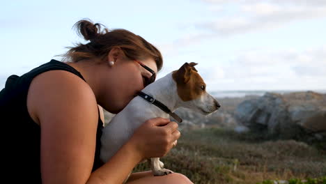 caucasian woman snuggles and pets her cute jack russell sitting on her lap