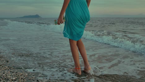 teenager girl with headphones walking on the beach. shot in slow motion