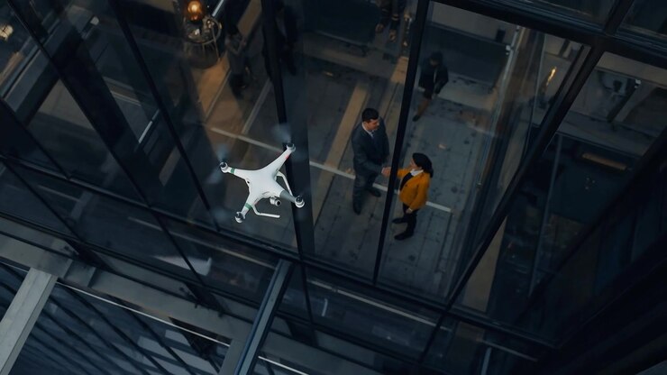 Drone pairando, fazendo com que um homem e uma mulher com casaco mostarda troquem um aperto de mão de negócios em um átrio de vidro.