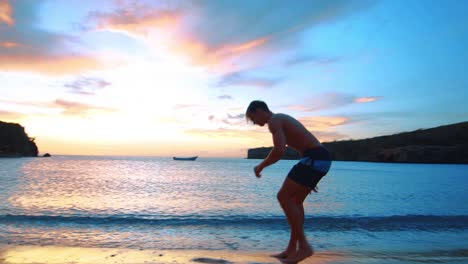 cámara lenta, hombre haciendo voltereta lateral en la playa caribeña durante la impresionante puesta de sol en curacao